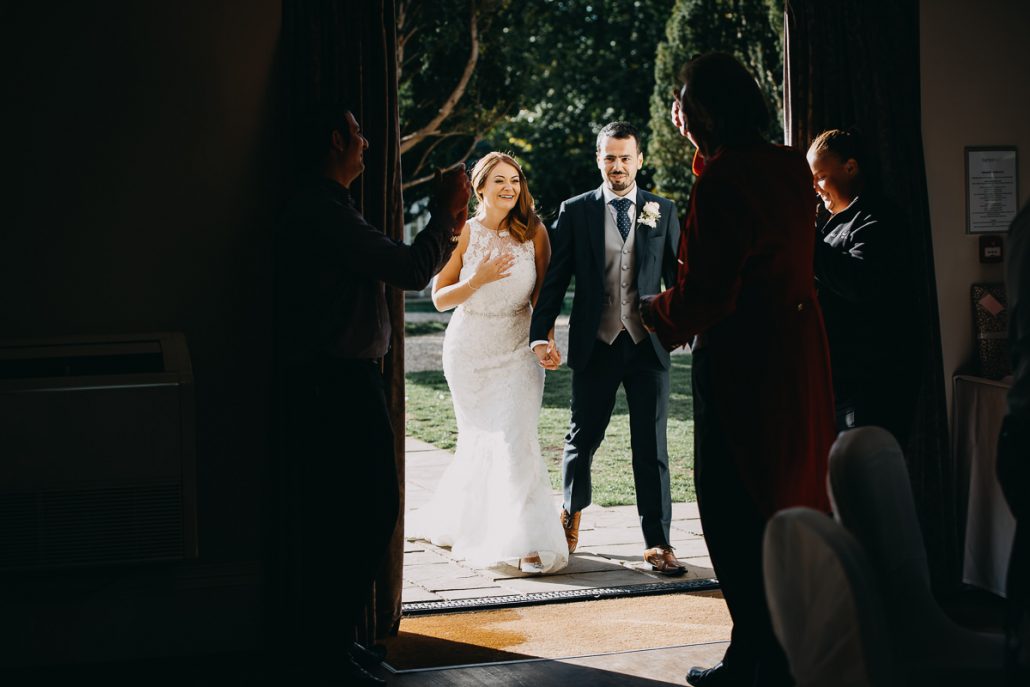 married couple enter room full of guests